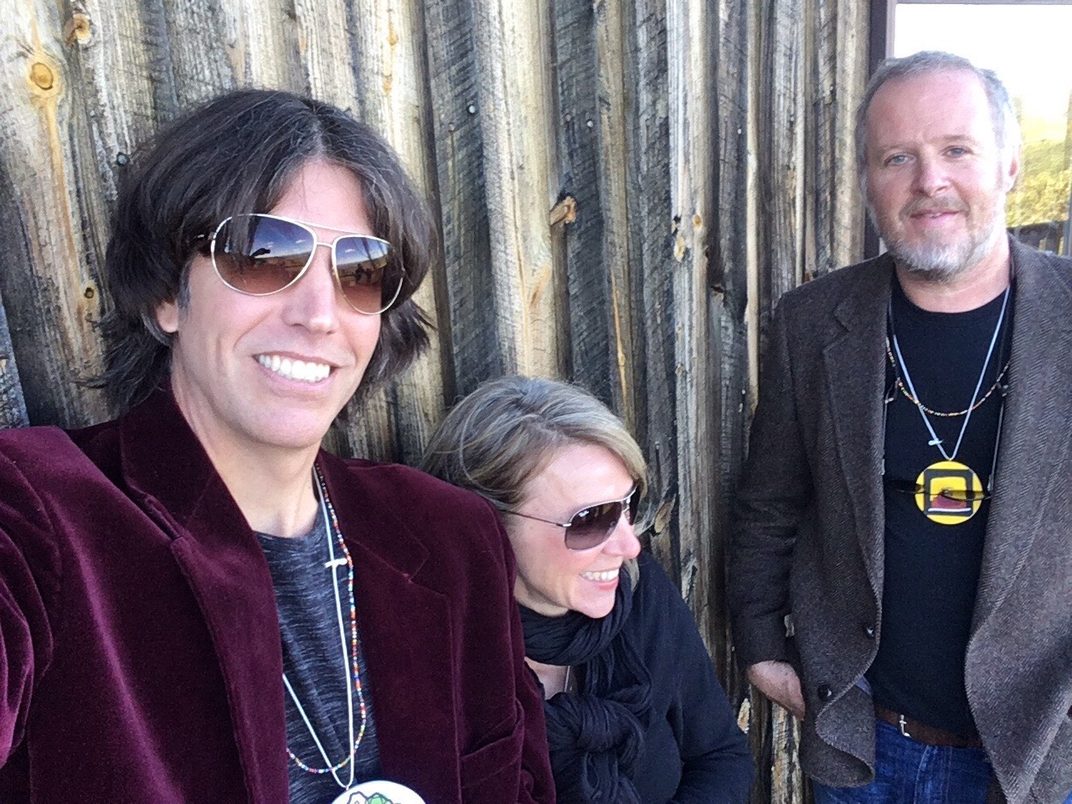The Pollocks band posing against a weathered wood fence