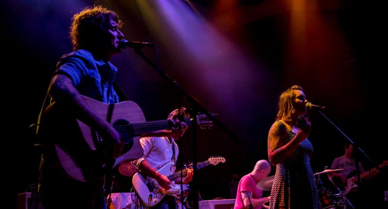 Band performing on stage under warm lights at the Press Play Music Series