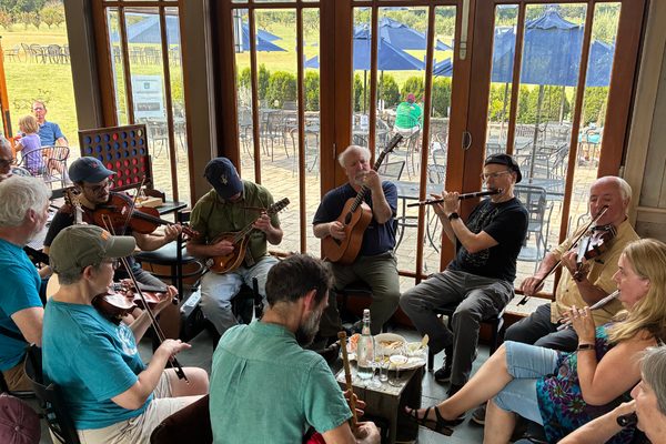 Musicians playing an Irish session around tables at Albemarle Ciderworks