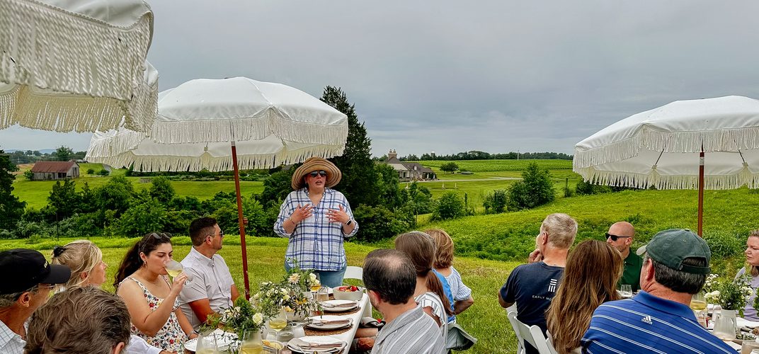 Guests seated at long tables under white canopies at the edge of the Early Mountain vineyard